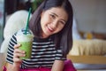 Smiling woman drinking matcha green tea latte in the morning at coffee shop. Portrait pretty Asian girl holding green tea glass in Royalty Free Stock Photo