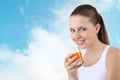 Smiling woman drinking orange juice vitamin on a sky background