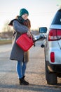 Smiling woman a driver pouring diesel in tank of her suv from red plastic can, an accident with empty car-tank on the road at Royalty Free Stock Photo
