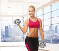 Smiling woman with dumbbells flexing biceps in gym Royalty Free Stock Photo