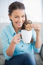 Smiling woman dunking cookie in coffee