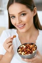 Smiling Woman Eating Nuts In Kitchen