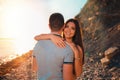 A smiling woman embraces a man. The view from the back. A young couple of lovers pose against the background of the beach, sea and Royalty Free Stock Photo