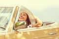 Smiling woman enjoying her summer cabrio ride holding her hat with one hand Royalty Free Stock Photo