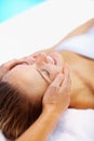 Smiling woman enjoying a peaceful face massage. Young woman pampering herself at the spa , a masseuse giving her a face Royalty Free Stock Photo