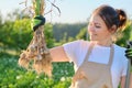 Smiling woman farmer gardener holding fresh dug garlic plant in hand Royalty Free Stock Photo