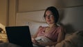 Smiling woman finishing work in night bed. Happy girl resting closing computer