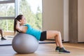 Smiling woman with fit ball flexing muscles in gym Royalty Free Stock Photo