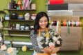 Smiling woman florist, small business flower shop owner, at counter, looking friendly at camera working at a special flower Royalty Free Stock Photo