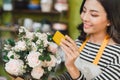 Smiling woman florist, small business flower shop owner, at counter, looking friendly at camera working at a special flower Royalty Free Stock Photo