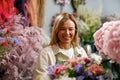 Smiling woman flower shop owner in apron looking on bouquet of flowers at florist store Royalty Free Stock Photo