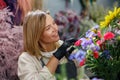 Smiling woman flower shop owner in apron looking on bouquet of flowers at florist store Royalty Free Stock Photo