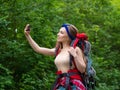 Smiling woman in the forest taking a selfie on a smartphone. Royalty Free Stock Photo