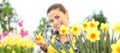 Smiling woman in garden of flowers touch daffodils, spring concept