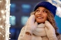 Smiling woman with garlands and holiday lights on festive Christmas or New Year fair