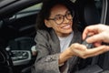 Close up of young smiling woman getting keys of a new car from the salesman. Concept for car rental Royalty Free Stock Photo