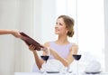 Smiling woman giving menu to waiter at restaurant