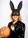 Smiling woman in Halloween bunny mask with pumpkin. Halloween party. Blonde girl in rabbit mask with Jack-o-lantern