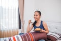 a smiling woman having breakfast sitting on a bed Royalty Free Stock Photo