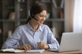 Smiling woman in headphones taking notes, studying online at home Royalty Free Stock Photo