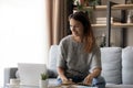 Smiling woman in headphones taking notes, using laptop at home Royalty Free Stock Photo