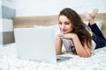 Smiling woman with her legs raised slightly in front of her laptop lying on the bed. Royalty Free Stock Photo