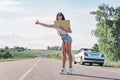 Smiling woman hitchhiker on road is holding a blank board.