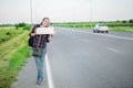 Smiling woman hitchhiker on the road is holding a blank board Royalty Free Stock Photo