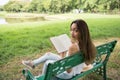 smiling woman hold book to read on park chair