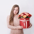 Smiling woman hold red gift box. Wall background. Concept of Valentine or Happy birthday. Bright and gorgeous bouquet of lovely Royalty Free Stock Photo