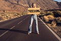 Smiling woman holding banner with freedom with the word freedom, posing outdoor over mountains landscape. Symbol of strength, Royalty Free Stock Photo