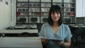 Smiling woman holding book in library. Friendly portrait with interactive atmosphere. Lifelong learning and community