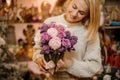 Smiling woman holding a bouquet of tender pink and purple color flowers with green stalks Royalty Free Stock Photo