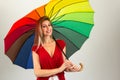 Smiling woman holding colorful umbrella. Blonde person and wearing red clothes. Isolated. Royalty Free Stock Photo