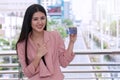Smiling woman holding a credit card and point fingers in city background. Attractive business woman get satisfy and happy