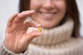 Smiling woman holding fish oil pill or vitamin D supplement. Capsule with omega3 Royalty Free Stock Photo