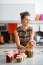 Smiling woman holding jar of preserved vegetables in kitchen Royalty Free Stock Photo