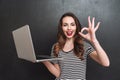 Smiling woman holding laptop computer and showing ok sign Royalty Free Stock Photo