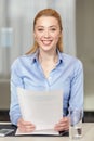 Smiling woman holding papers in office Royalty Free Stock Photo