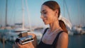 Smiling woman holding photocamera on evening waterfront close up. Carefree lady Royalty Free Stock Photo