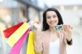 Smiling woman holding purchases and plastic bank card in shopping mall Royalty Free Stock Photo