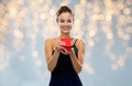 Smiling woman holding red gift box over lights Royalty Free Stock Photo