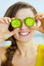 Smiling woman holding slices of cucumber in front of eyes Royalty Free Stock Photo