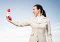 Smiling woman holds red handset phone on distance