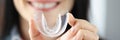 Smiling woman holds transparent plastic mouth guard in her hand