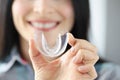 Smiling woman holds transparent plastic mouth guard in her hand