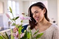 Smiling Woman At Home Arranging Bouquet Of Flowers In Glass Vase