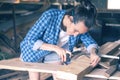 Smiling woman in a home workshop measuring tape measure a wooden Board before sawing, carpentry Royalty Free Stock Photo