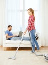 Smiling woman with hoover and man with laptop Royalty Free Stock Photo