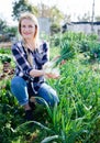 Smiling woman horticulturist holding harvest of green onion